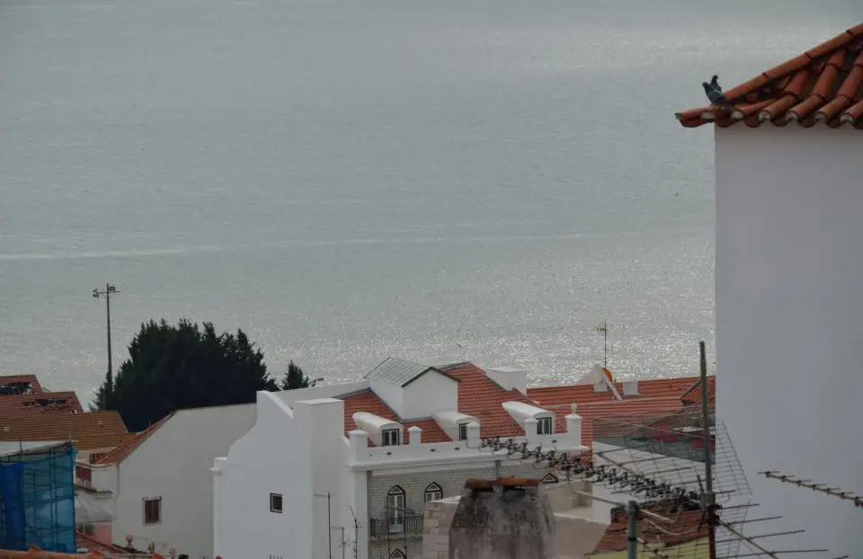 Von der Alfama im Zentrum von Lissabon eröffnen sich immer wieder schöne Ausblicke. Hier siehst du den Tejo über den Dächern schimmern.