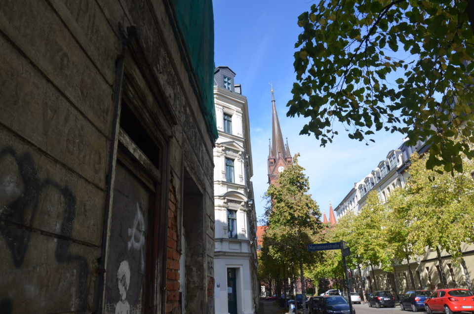 Hier siehst du die Heilig-Kreuz-Kirche mit ein einem verfallenen und einem sanierten Gründerzeithaus. Das spannende Gesamtbild findest du nördlich der Leipziger Eisenbahnstraße.