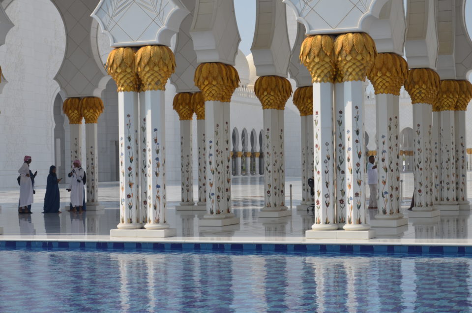 Blick über einen Pool in die Scheich-Zayid-Moschee, die du bei deiner Abu Dhabi Zwischenlandung ansteuern solltest.